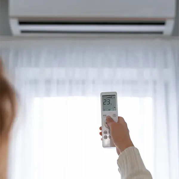 Personne réglant la température d'une climatisation